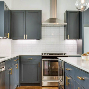 دکوراسیون طوسی طلایی آشپزخانه نئوکلاسیک با کابینت های طوسی تیره و دستگیره های طلایی